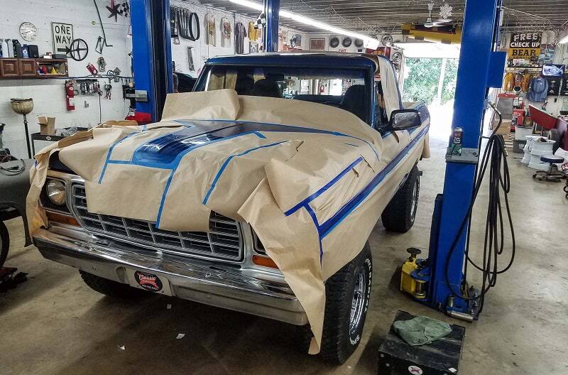 Front view of blue Bronco with paper taped around it in garage