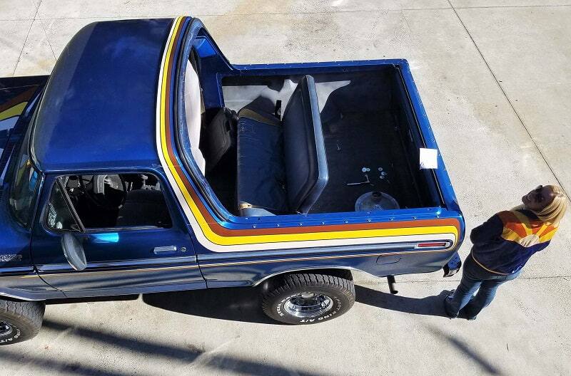 Overhead shot of Bronco girl next to blue Bronco with trunk hatch off