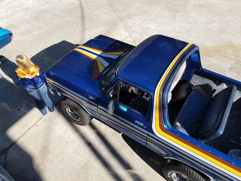 Overhead shot of Bronco girl next to blue Bronco with trunk hatch off