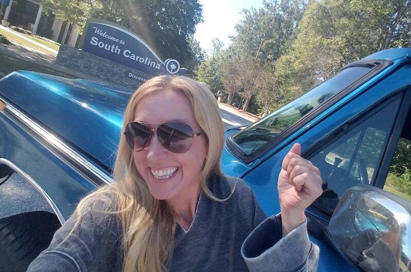 Bronco girl posing with her blue Bronco in front of South Carolina sign