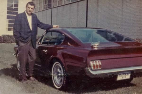 Man standing next to red Mustang