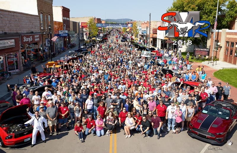 Overhead shot of big crowd of people on the road with various Mustangs