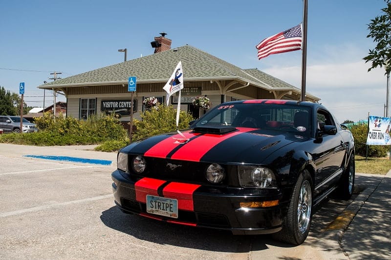 Front of black with red stripes Mustang in front of building