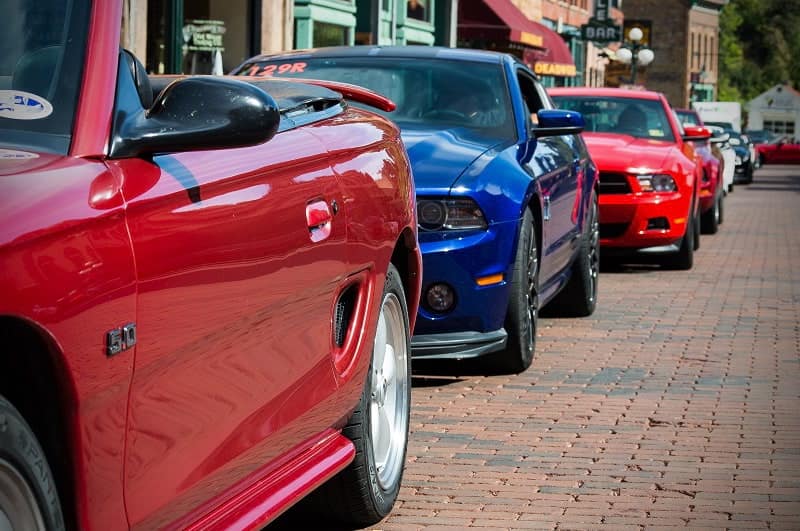 Close up of front of red and blue Mustangs in a line