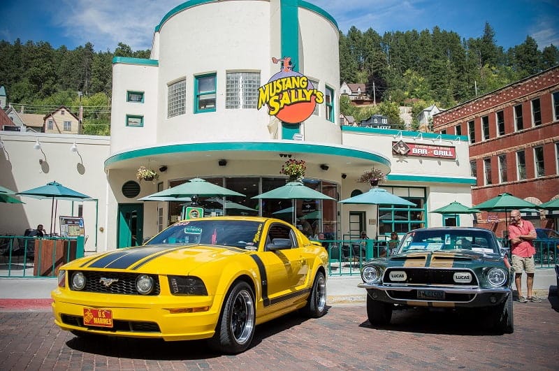 Yellow and green Mustangs in front of Mustang Sally bar