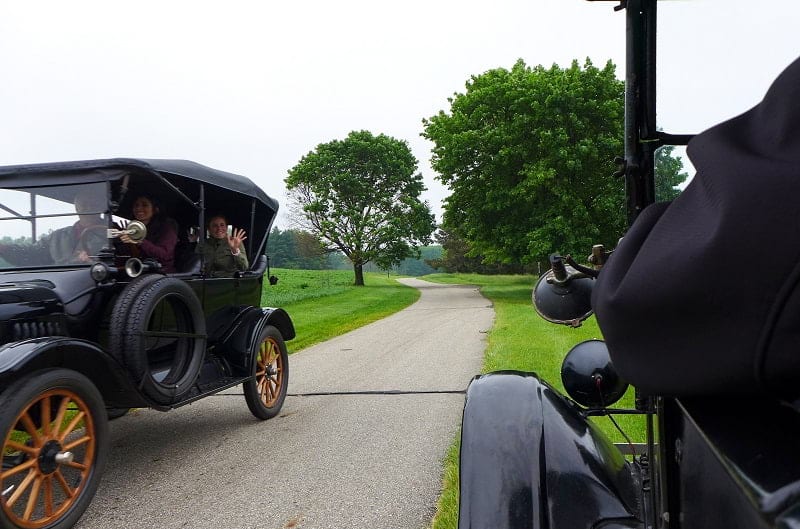 Front profile of black Model T passing another black Model T