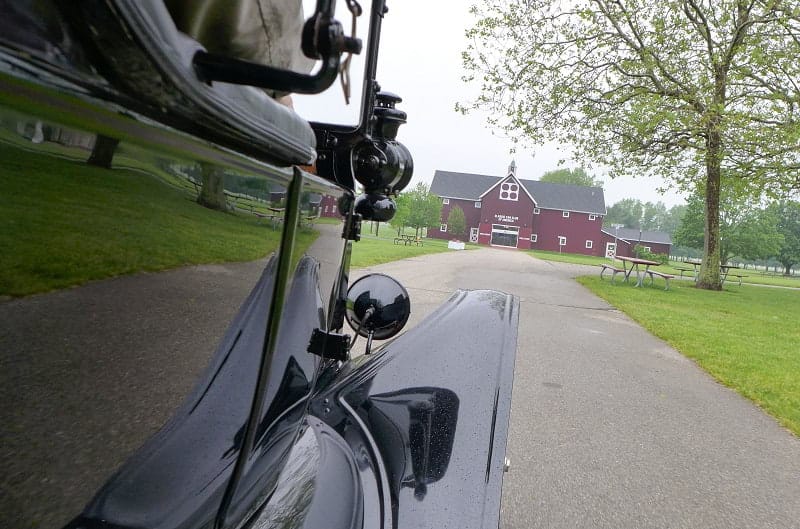 Side profile of black Model T with red barn in front of it