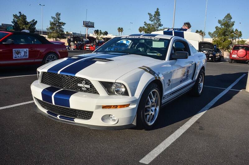 Front profile of white Shelby GT with blue stripes in parking lot