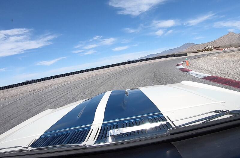 Front view through the window of the white Shelby GT of the hood with blue stripes on the track