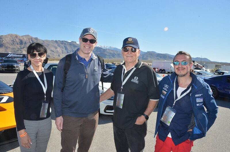 Four people are pictured in a parking lot full of Shelbys