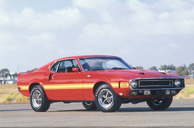 Front profile of a red with yellow stripe Shelby GT on a road