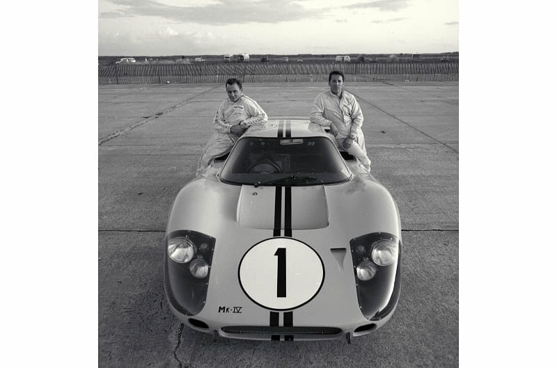 Black and white image of two men leaning on a front facing GT