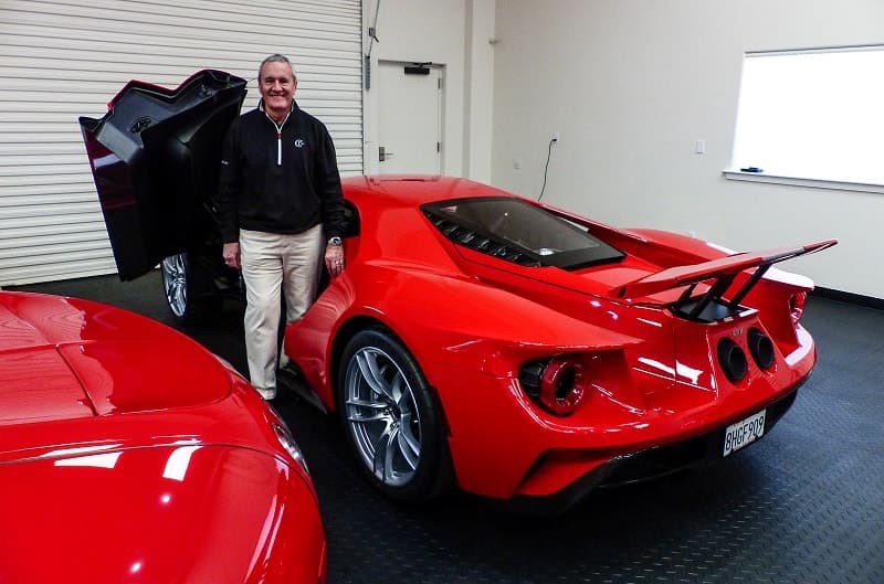 Bill Swanson next to a rear facing red GT with driver door up