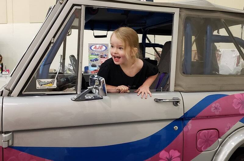 Close up of young girl in the front seat of the gray blue and pink Bronco