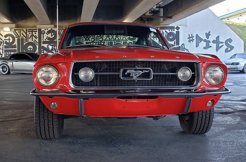 Close up front end of red Mustang under bridge