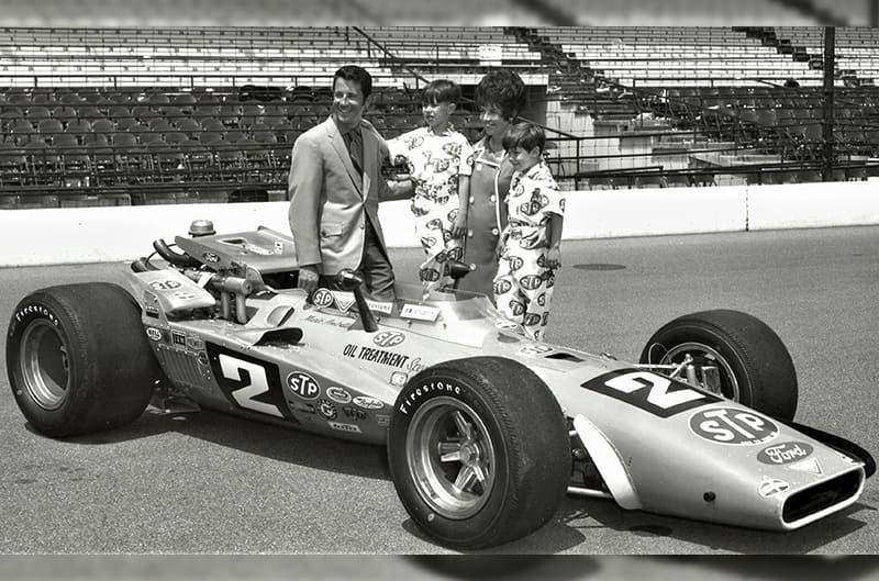 Black and white photo of Granatelli and family posing next to indycar