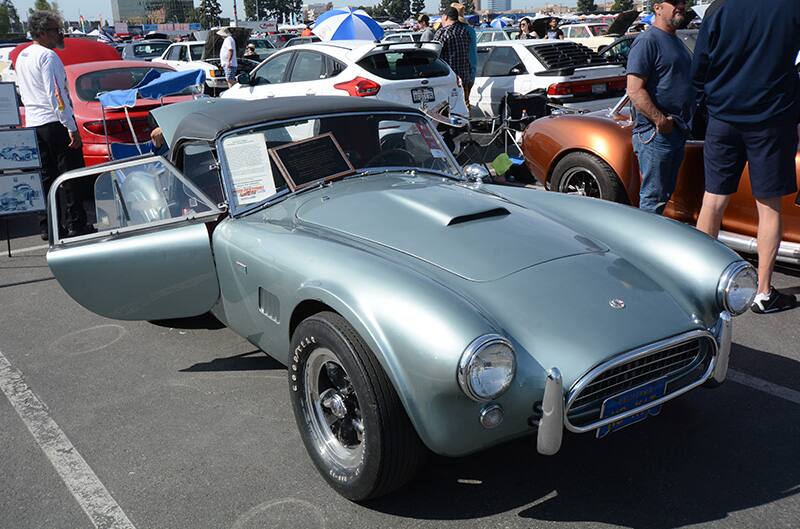 Front of light blue Shelby Roadster with passenger door open in parking lot