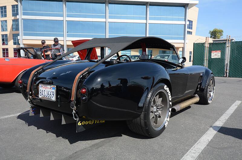 Rear of black Cobra roadster in parking lot