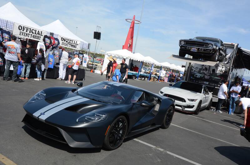 Front profile of black GT in front of small tents in a parking lot of people