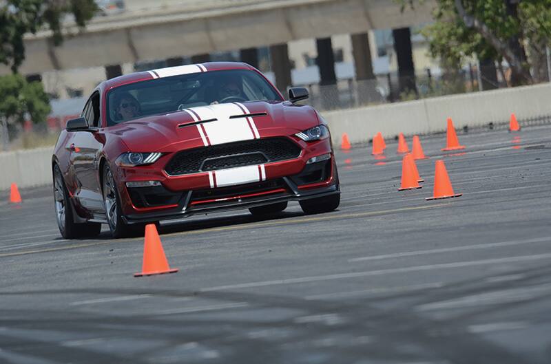 Front of red Shelby Mustang driving in the parking lot through orange cones