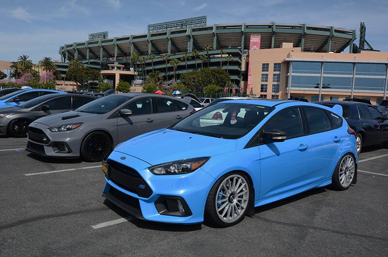 Front profiles of a blue and dark gray Focus in parking lot