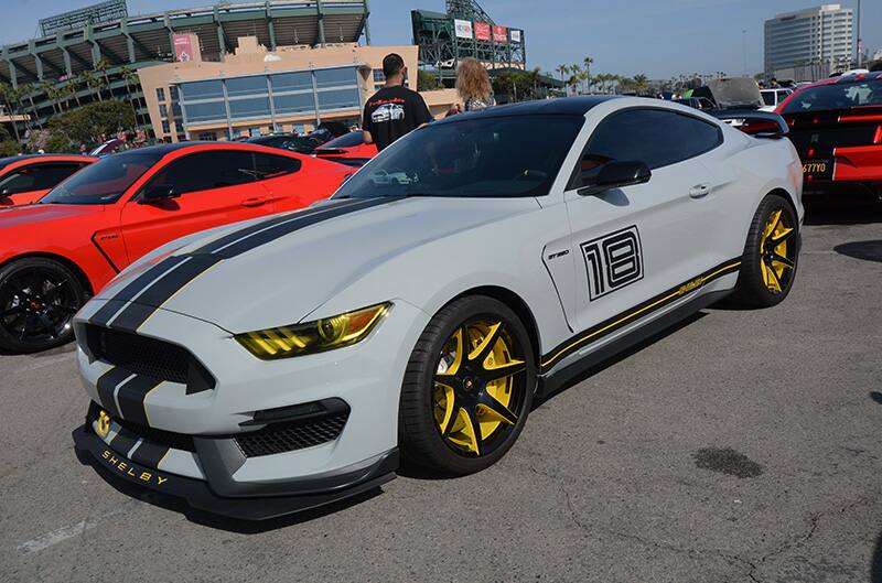 Front profile of white Shelby Mustang with yellow details in parking lot