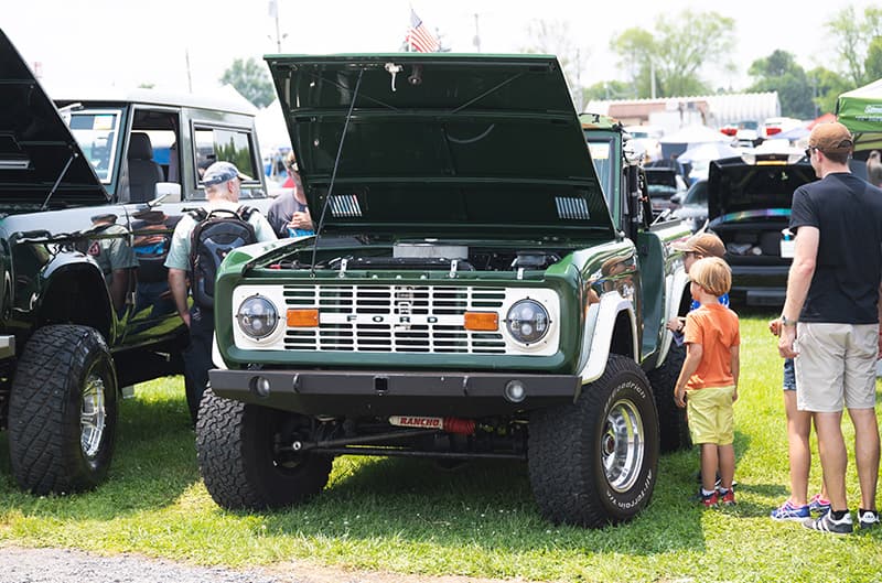 Front of green Bronco with hood open parked in the grass