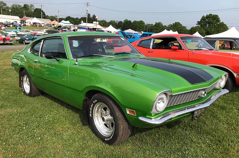 Front profile of a green Maverick with black stripe on hood parked on the grass