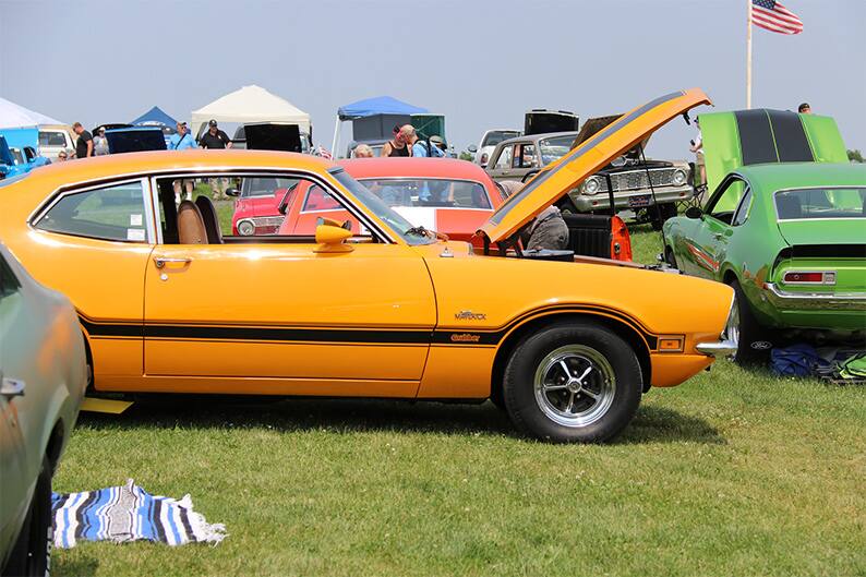 Profile of a yellow Maverick on the grass with hood open on the grass