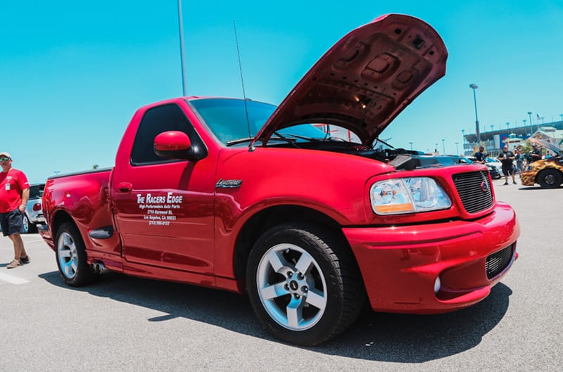 Profile of red SVT Lightning pickup with hood open in the parking lot