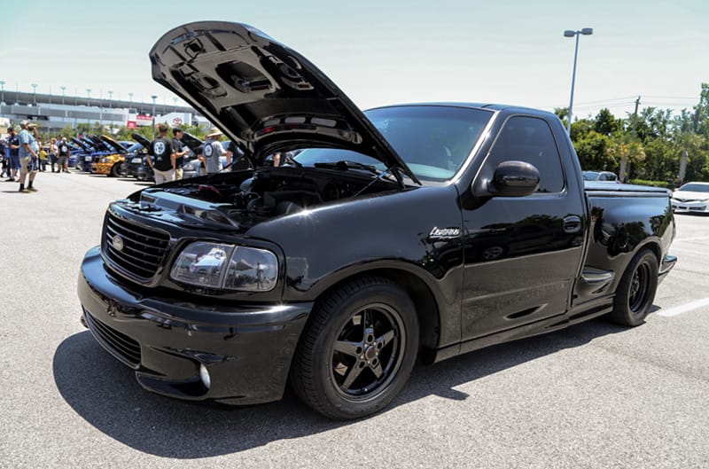 Front profile of black SVT Lightning with hood open in parking lot