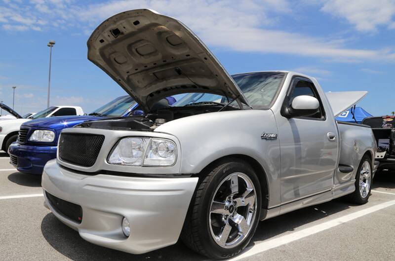 Front profile of silver SVT Lightning with hood and trunk open in parking lot