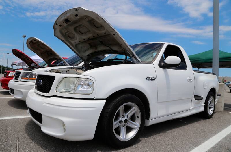 Front profile of white SVT Lightning with hood open in parking lot