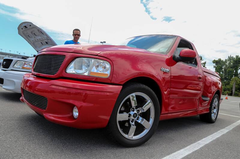 Close up front profile of red SVT Lightning in parking lot with man looking at it