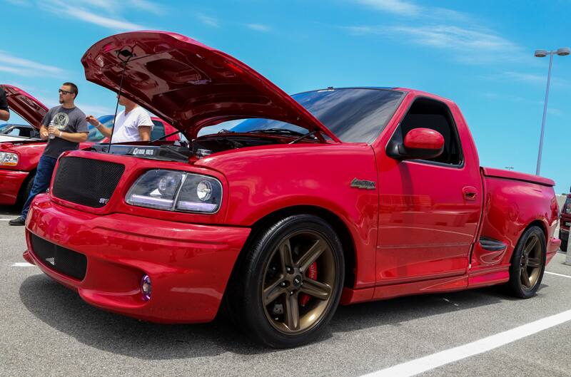 Front profile of red SVT Lightning with hood open in parking lot