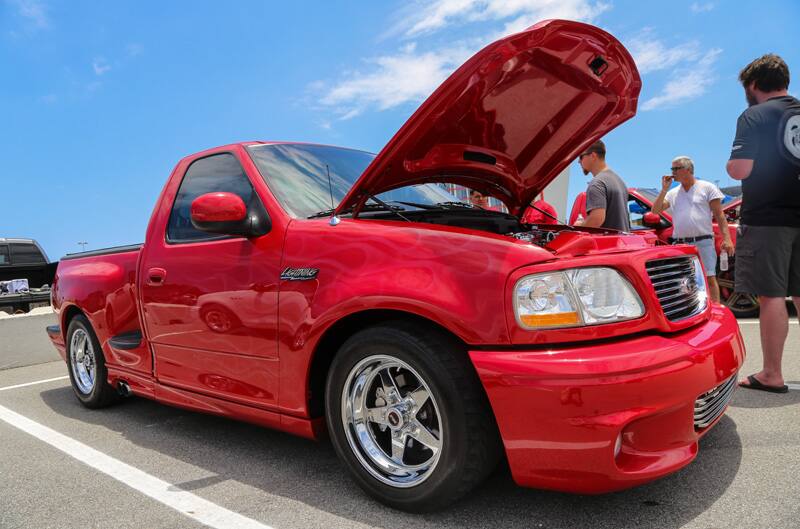 Front profile of red SVT Lightning with hood open in parking lot