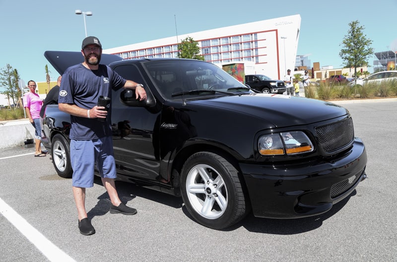 Man posing next to black SVT Lightning in parking lot