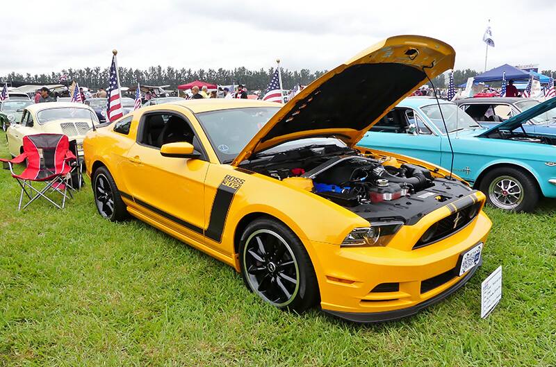 Front profile of yellow Mustang Boss 302 with hood open on the grass