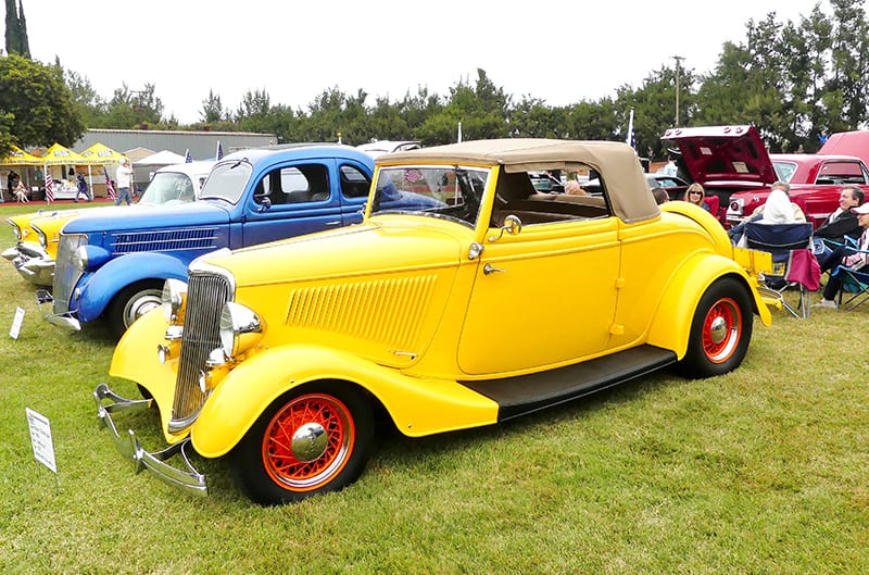 Profile of vintage yellow Ford on display on the grass