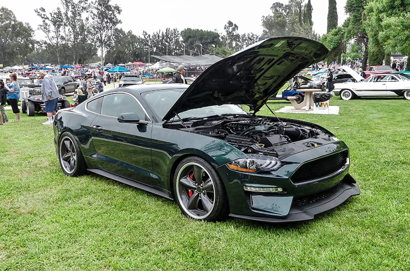 Front profile of green Mustang Bullitt with hood open on grass field at car show