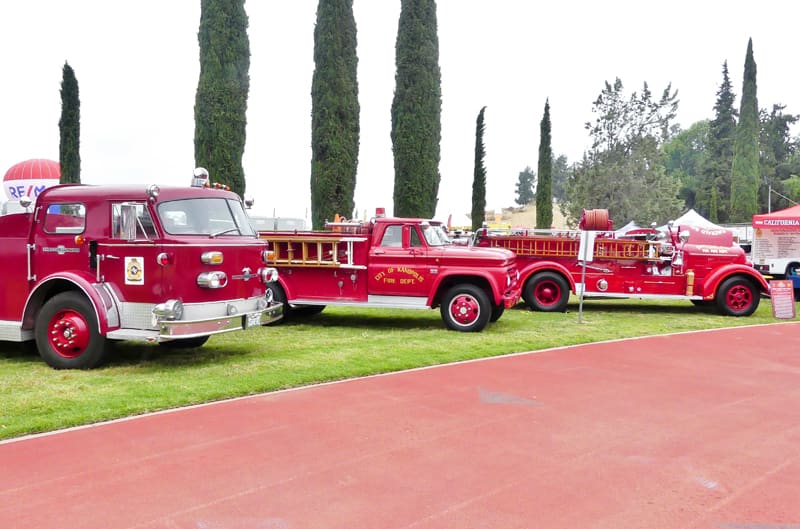 Three red fire trucks on in a line on the grass