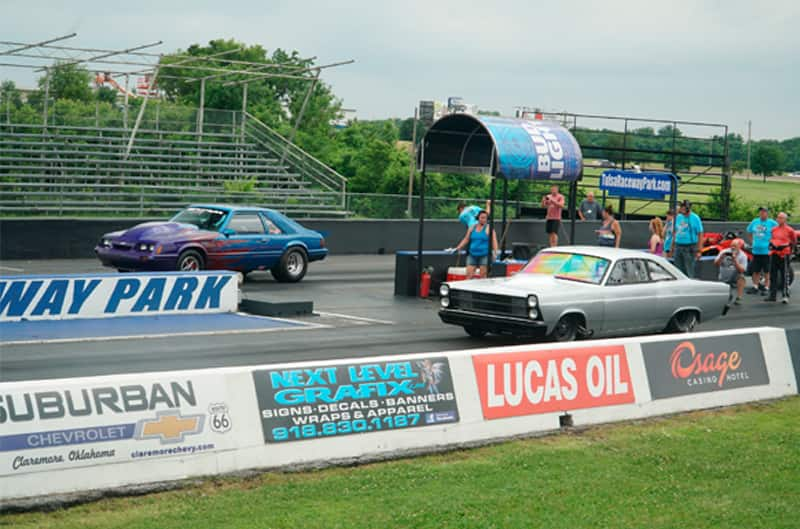 Profile of a silver Mustang and purple and blue Mustang on a track