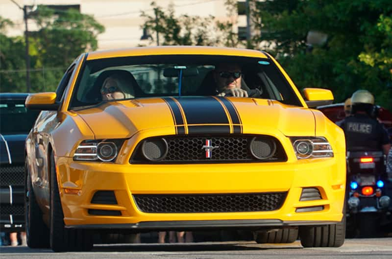 Close up front of a yellow Mustang on the road