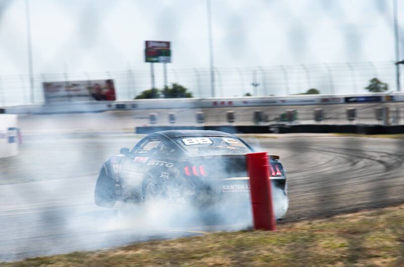 Rear of Chelsea DeNofas black Mustang in a cloud from drifting