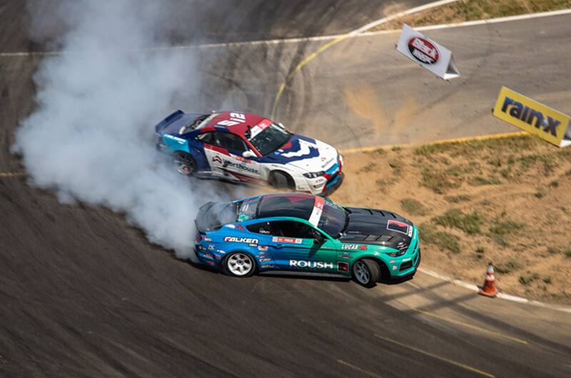 Overhead profile shot of Justin Pawlak drifting his Mustang next to another Mustang