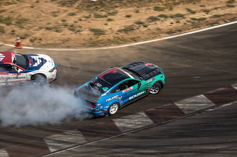 Overhead shot of Justin Pawlak drifting his blue and green Mustang on the track