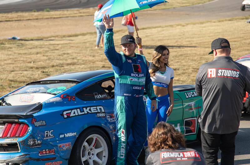 Justin Pawlak in front of his Mustang waving to fans