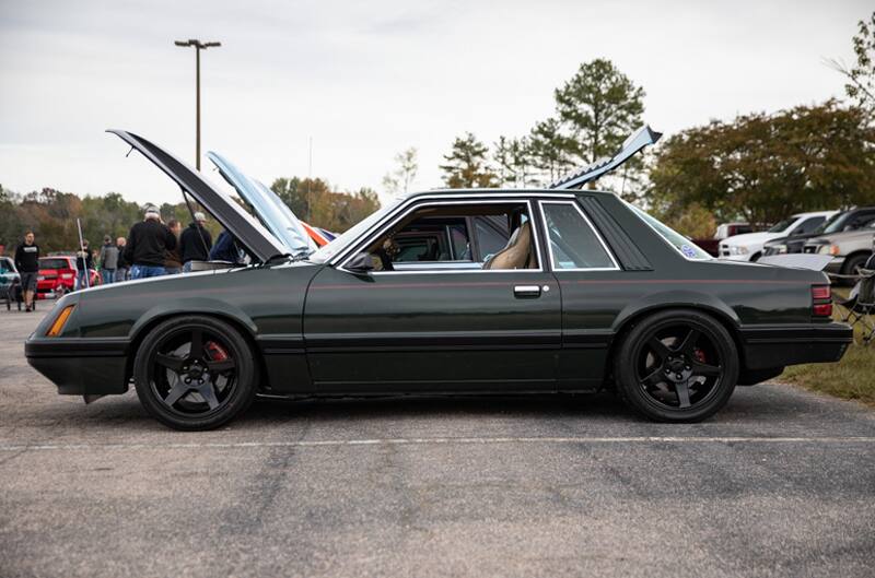 Profile of black Mustang with hood open in parking lot