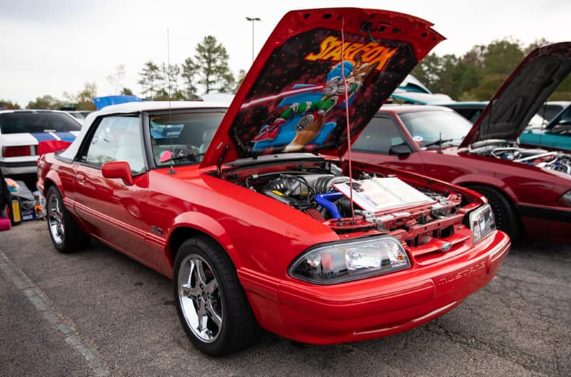 Front profile of red Mustang droptop with hood open and StarFox image painted under the hood