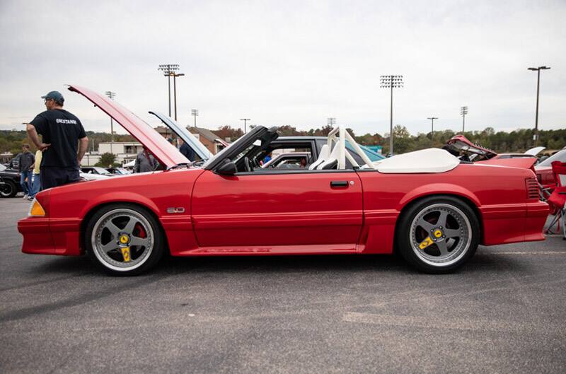 Profile of red Mustang with roof down and hood up in parking lot